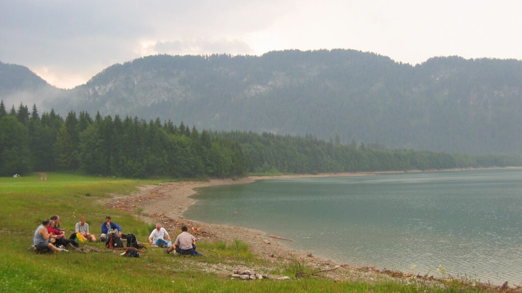 Team sitzt zusammen am Ufer eines Sees